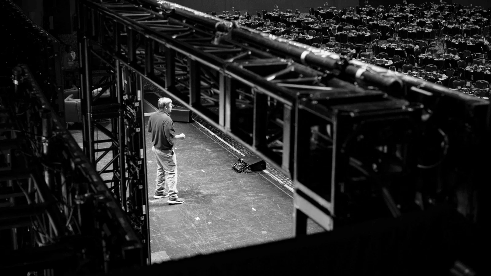 Corporate event stage setup with overhead truss system and production manager reviewing ballroom layout