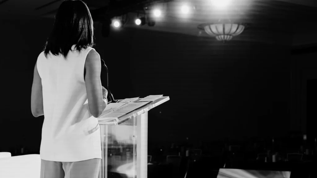 Corporate event speaker at podium under stage lighting before audience arrival
