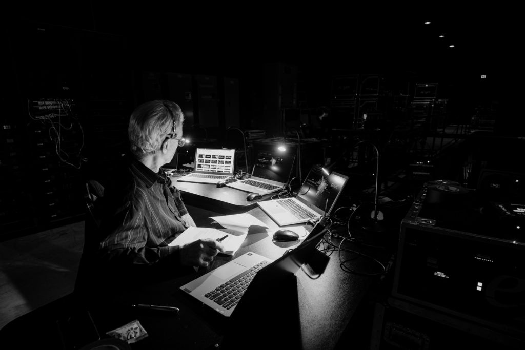 Technical director managing live event production from control room with multiple screens and laptops in Atlanta
