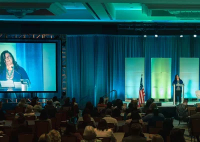 General session conference with IMAG screen, stage lighting, and keynote speaker presenting to audience by Innovent Technologies