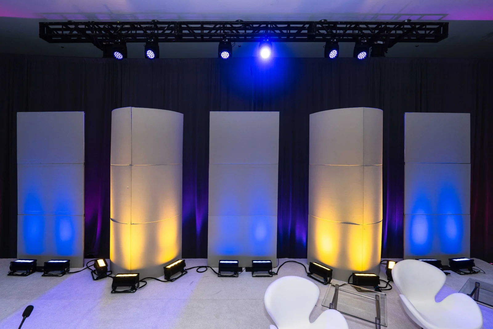 Custom stage design with curved panel columns and color wash lighting for corporate event production by Innovent Technologies