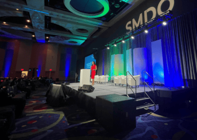 Wide view of SMDO 2026 executive conference stage with scenic panels and architectural lighting