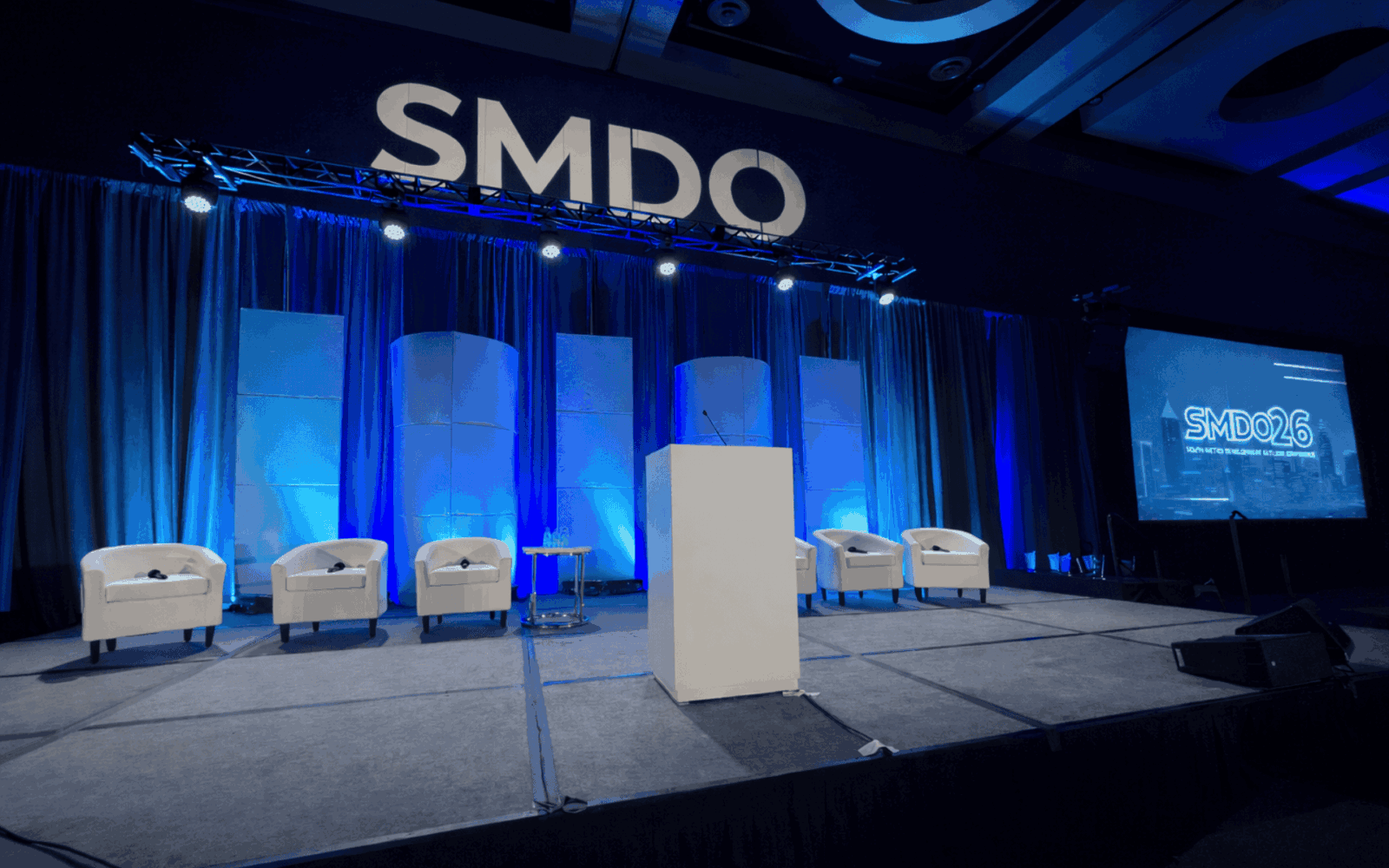 SMDO 2026 Outlook Conference executive stage with scenic panels and dual projection screens