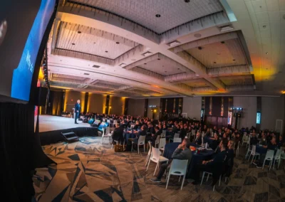 Campari Group general session in Atlanta with audience seated at round tables facing a lit stage with presenter, LED screen, and professional event lighting by Innovent Technologies