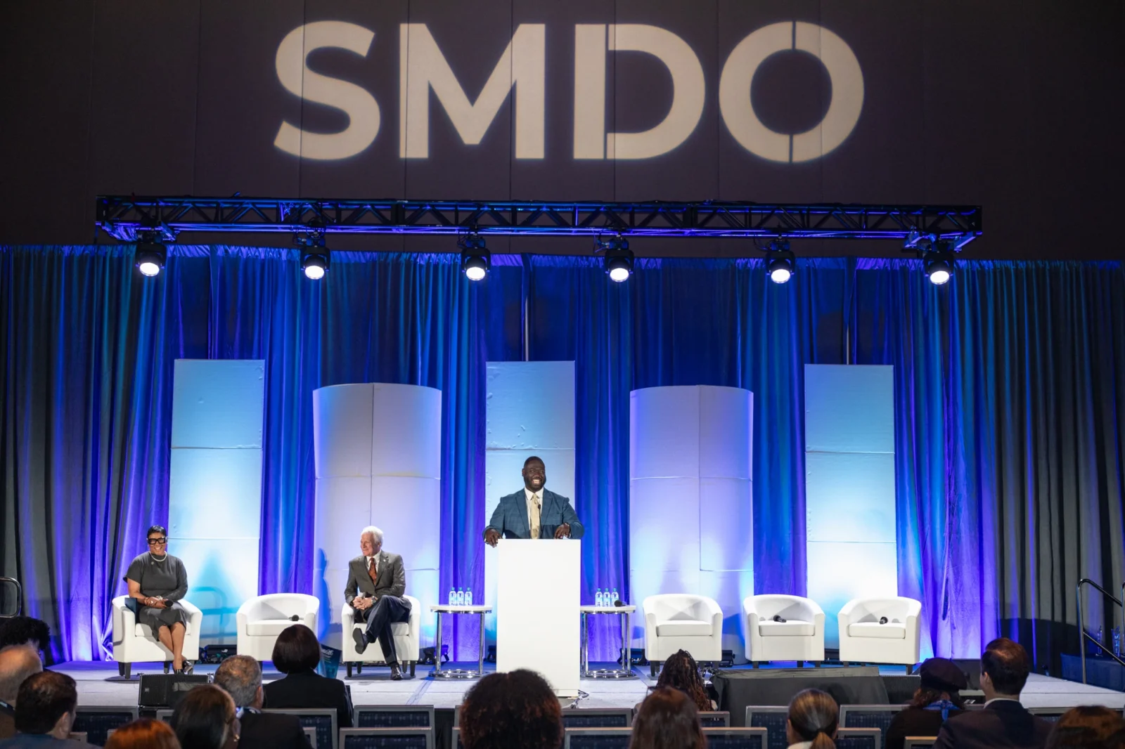 Panel session with speaker at podium, stage lighting, and scenic panels for corporate conference production by Innovent Technologies