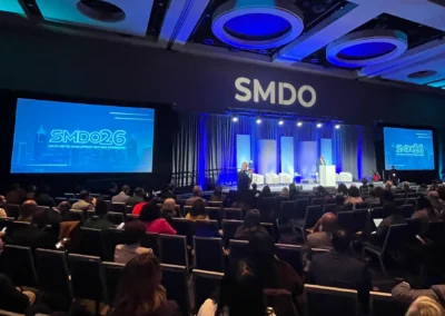 Full room view of SMDO 2026 general session with audience, stage, dual screens, and lighting production by Innovent Technologies