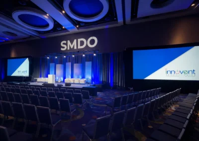 SMDO 2026 conference stage setup with seating, dual projection screens, and blue lighting design by Innovent Technologies