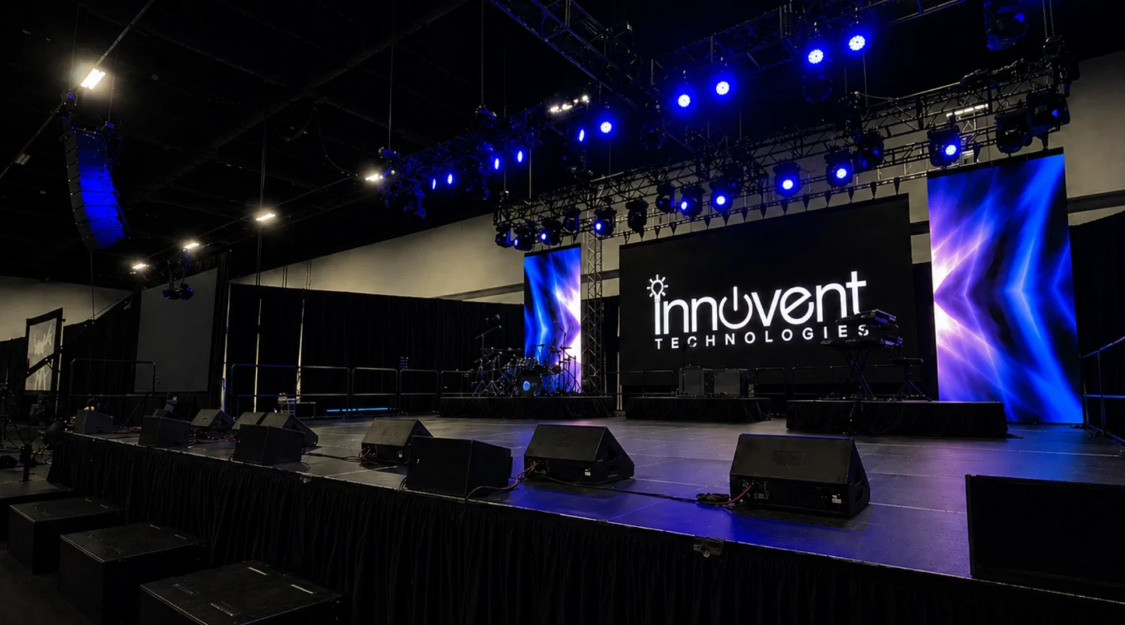 Integrated event technology stage with LED wall, lighting rig, and AV production systems designed for a corporate conference environment