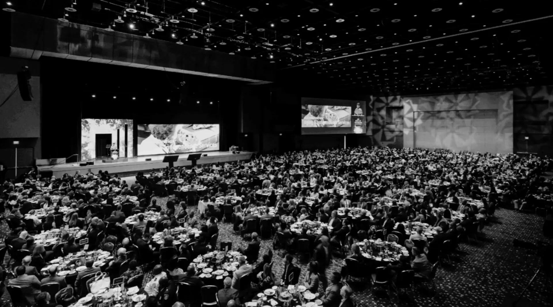 Large corporate conference general session with hundreds of attendees, LED screens, stage presentation, and integrated AV production