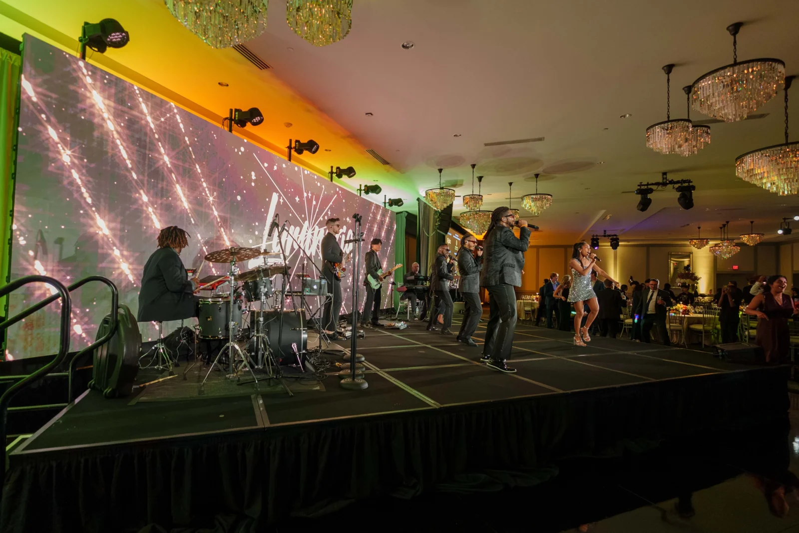 Live band performing on stage at a gala with a large LED video wall, professional stage lighting, and audiovisual production.