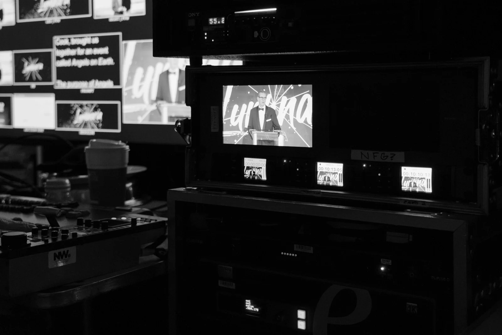 Behind-the-scenes video production equipment displaying a live speaker feed during a gala presentation.